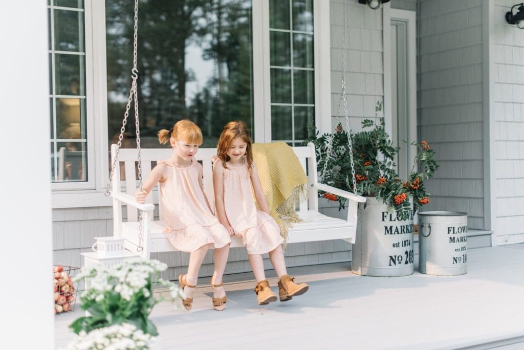 2 girls sit on a porch swing