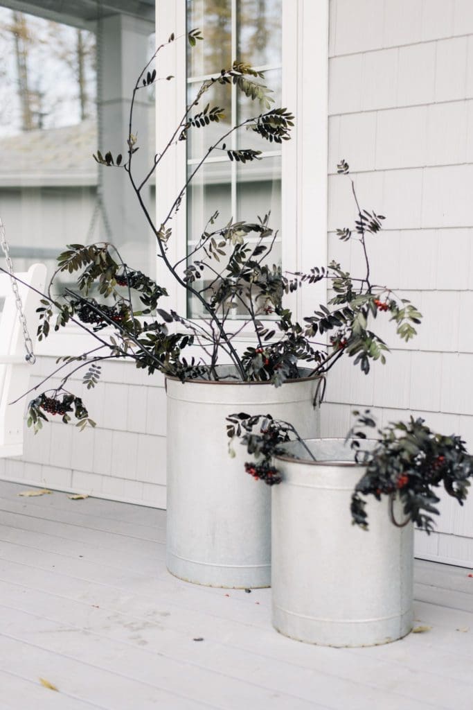 Spray painted black branches sit in galvanized tubs for Halloween