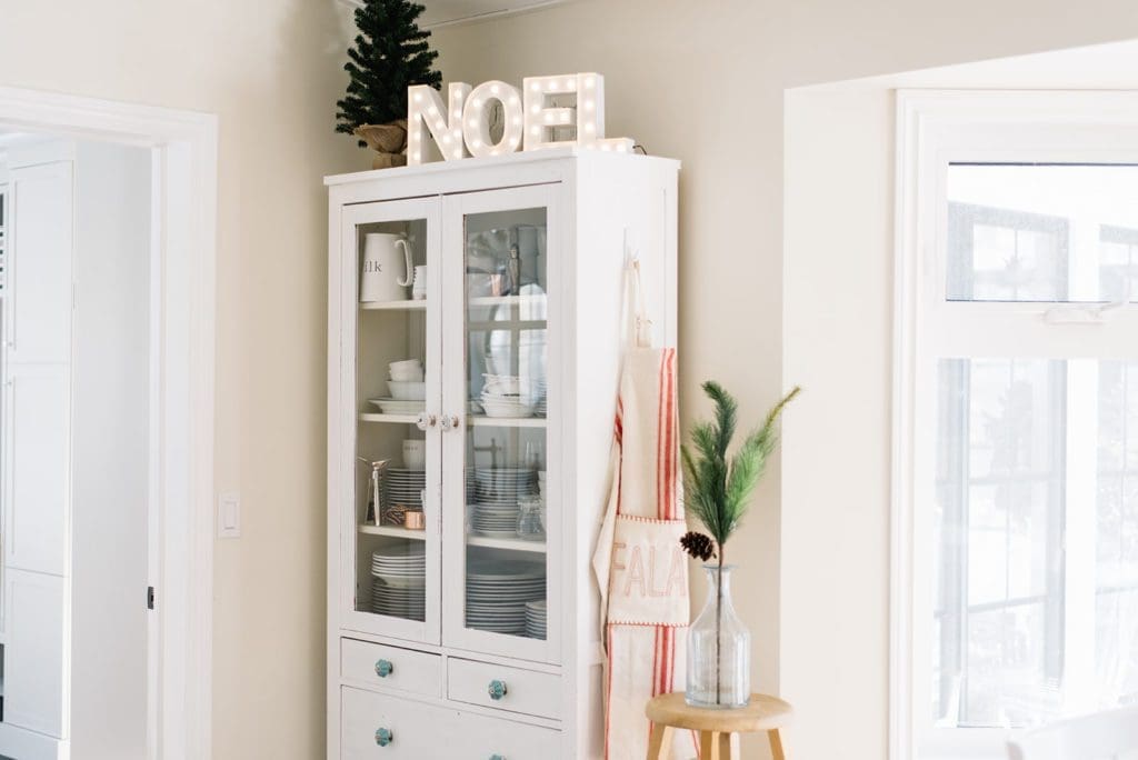 Christmas decor in the dining room including a lit Noel sign and hanging festive apron
