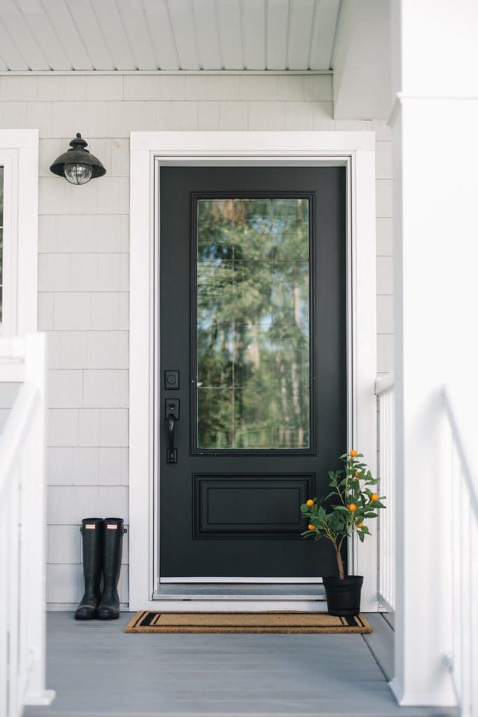 black front door with orange tree and boots sitting beside