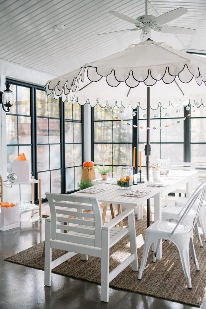 sunroom set up for a Halloween party with an umbrella and orange candles