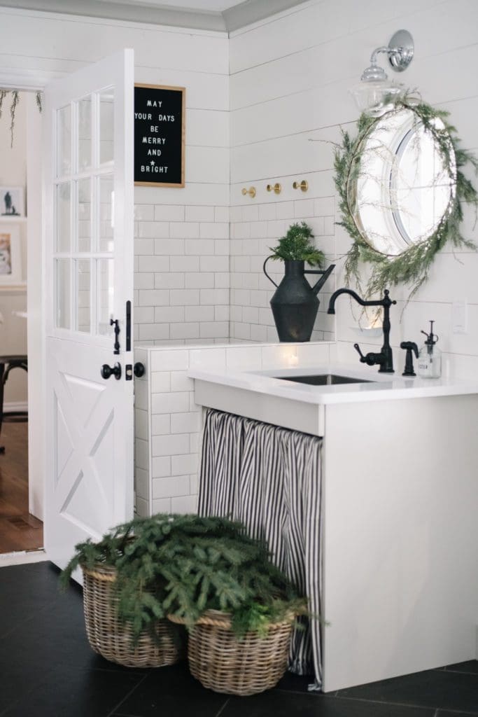 minimal holiday home decor -a Christmas mudroom sink decorated with cedar garland