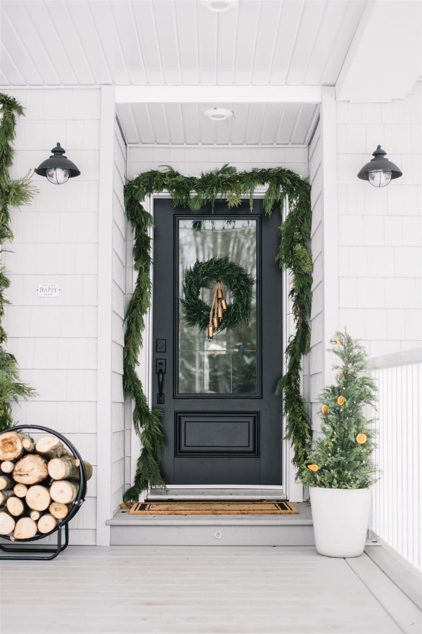 Neutral Scandinavian style front door decorated with fresh greens, bells and orange slices