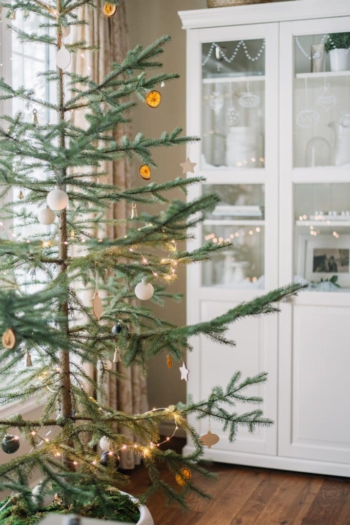 A sparse Christmas tree with white ornaments and dried oranges