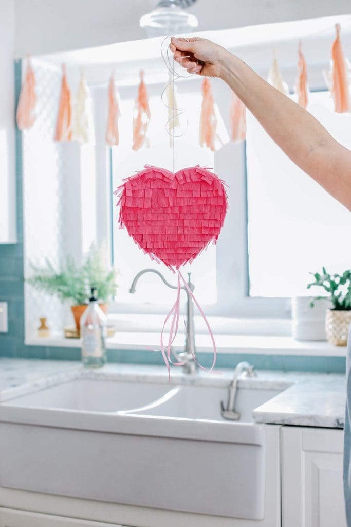 holding up a mini heart pinata