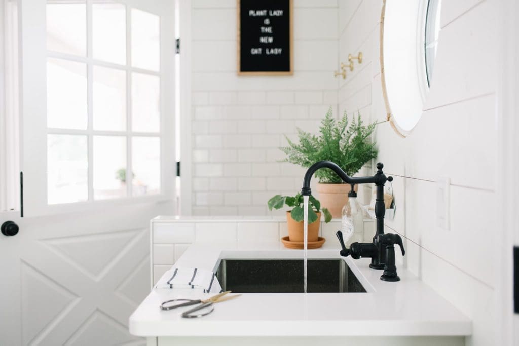 Watering houseplants in a neutral farmhouse mudroom