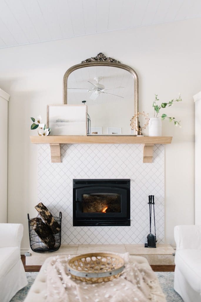 fireplace with white tile and white oak mantle with gold mirror