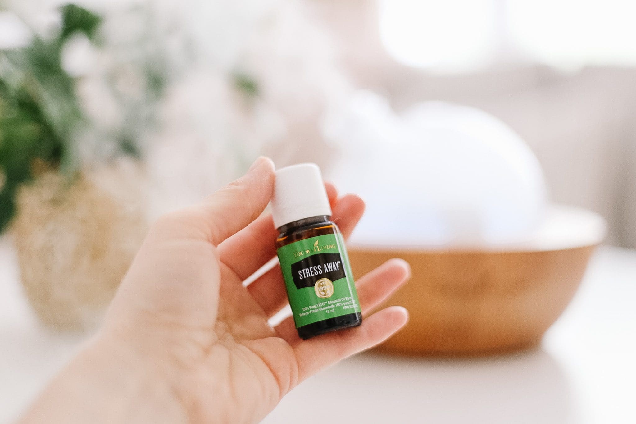 Bottle of Stress away essential oil held in front of diffuser