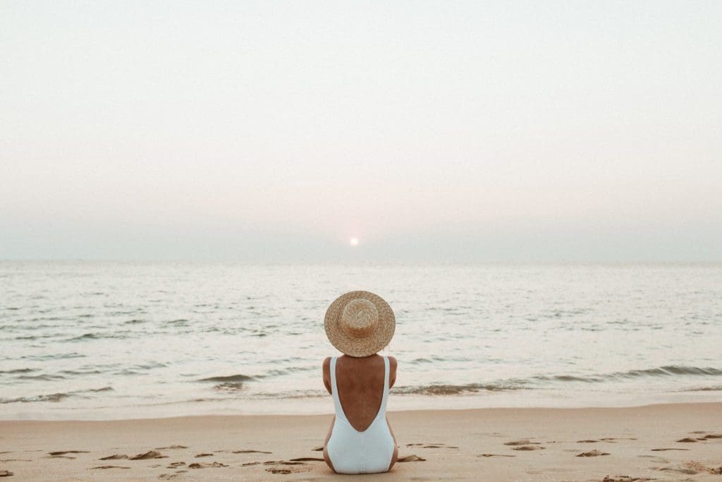 A person sitting on the beach looking out at the ocean
