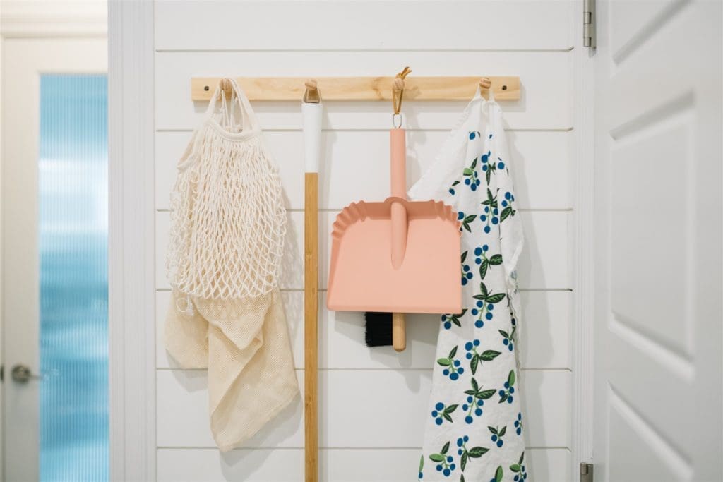 peg rail with pink dustpan hanging on it