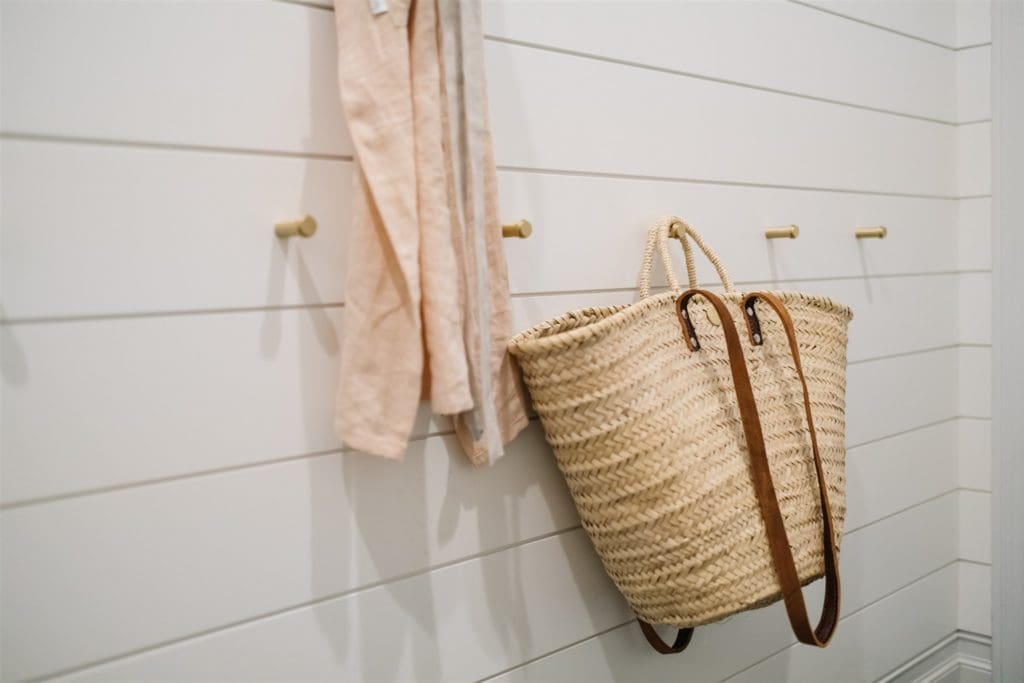 a woven market basket hanging on a brass hook