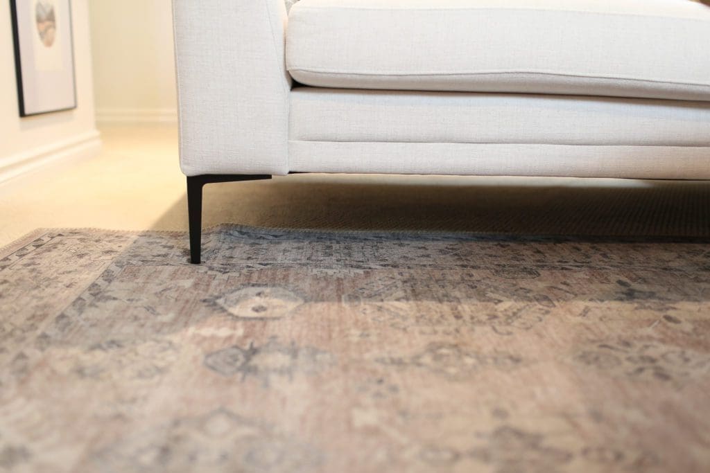 pink patterned rug under a sectional with black metal legs