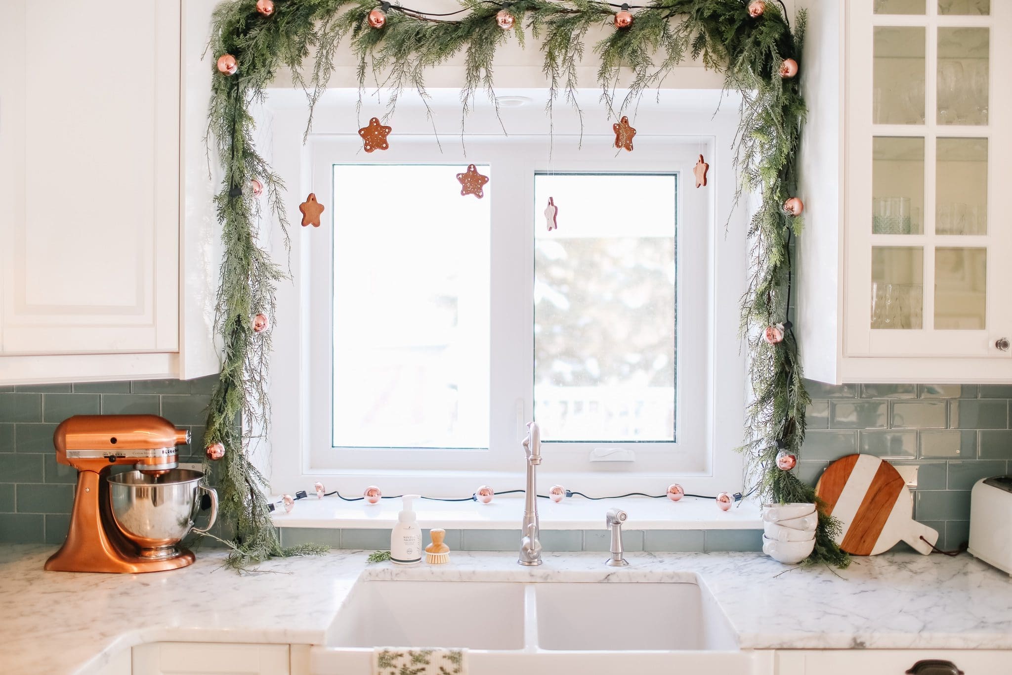 kitchen window decorated with Christmas garland and gingerbread cookies shaped like stars