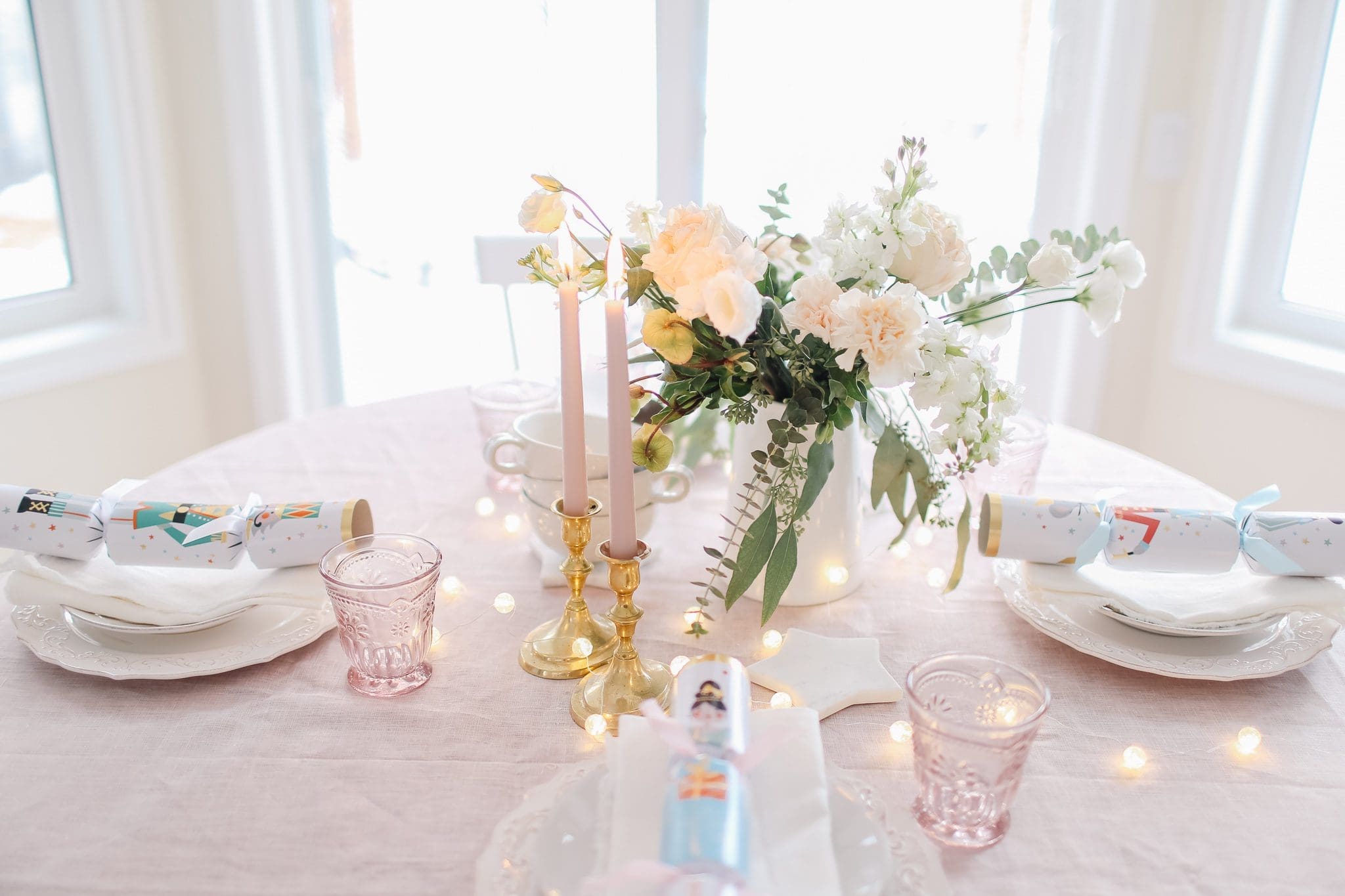 A vase of flowers on a table with fairly lights and candles