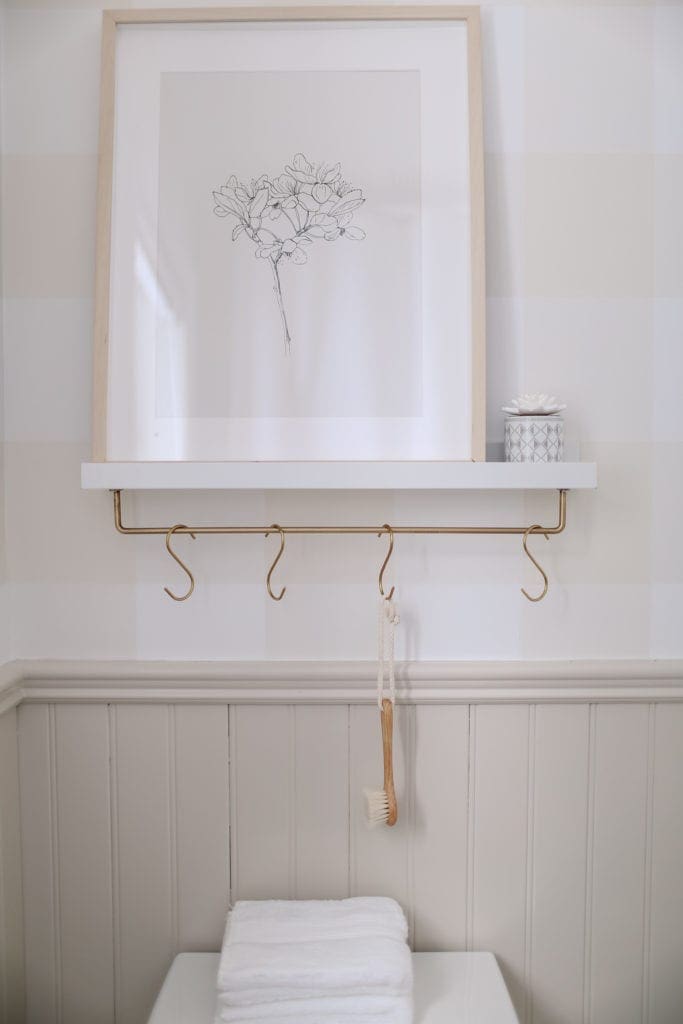 A shelf with a brass rod and hooks mounted beneath