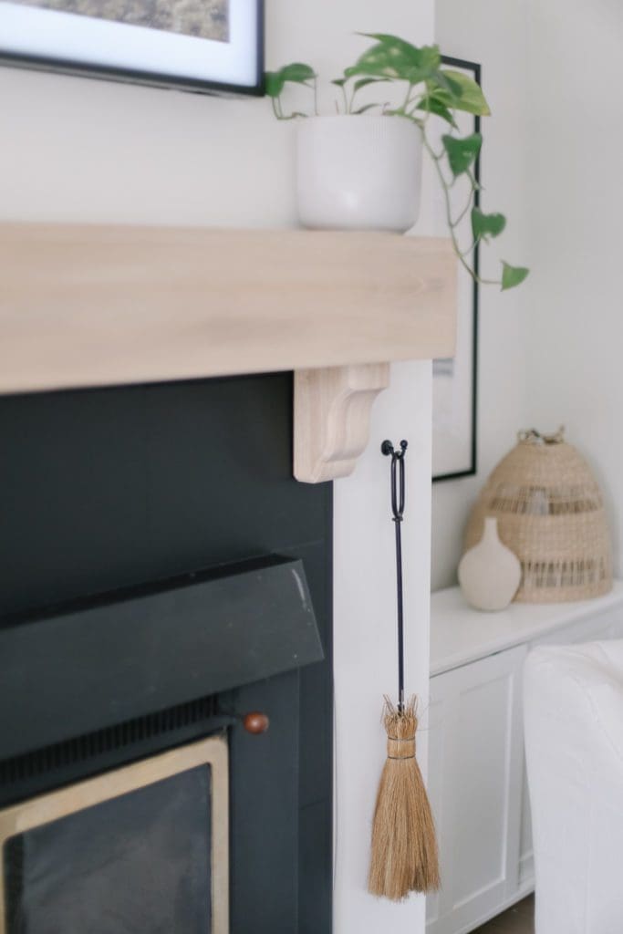 A mini broom hung beside a fireplace