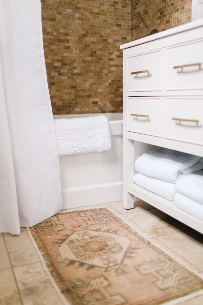 A bathroom vanity with white towels folded on the bottom shelf