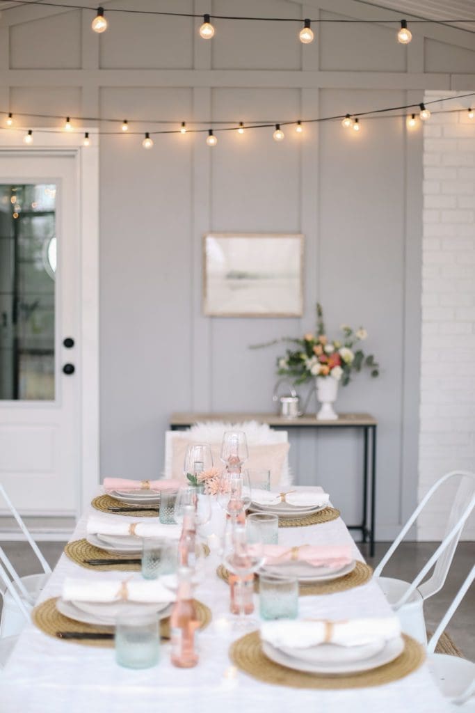 A dining room table set with pink flowers and napkins