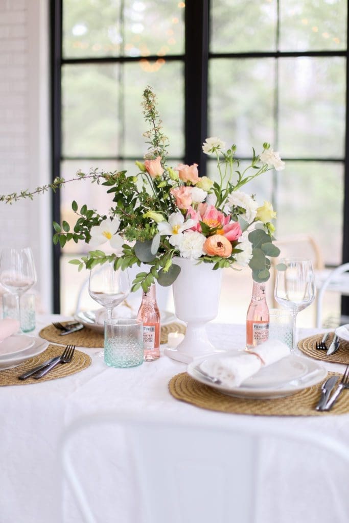 A vase of flowers on a mother\'s day tablescape next to a window