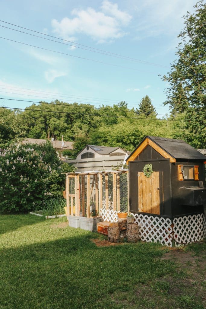 A black and cedar chicken coop in a grassy yard
